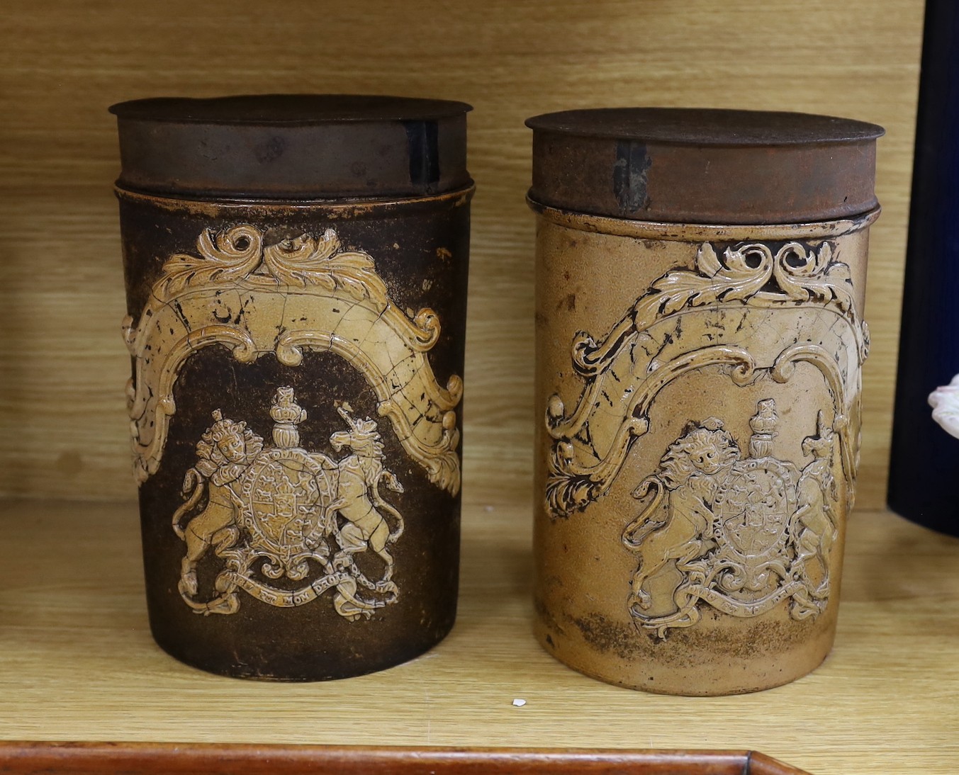 A pair of 19th century cylindrical salt glazed stoneware canisters, with Royal coat of arms sprigging, 26cm tall